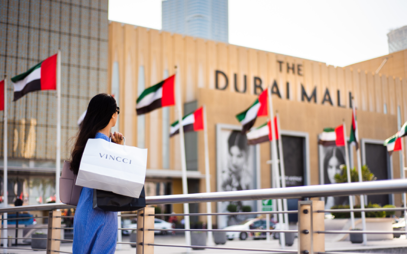 Woman shopping outside The Dubai Mall with UAE flags in the background