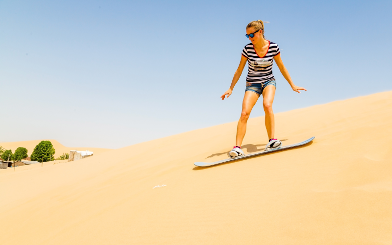 Woman sandboarding in Dubai desert
