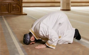 Man in traditional attire praying in mosque