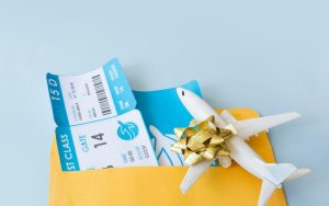 Flight tickets in an envelope with a gift-wrapped airplane model