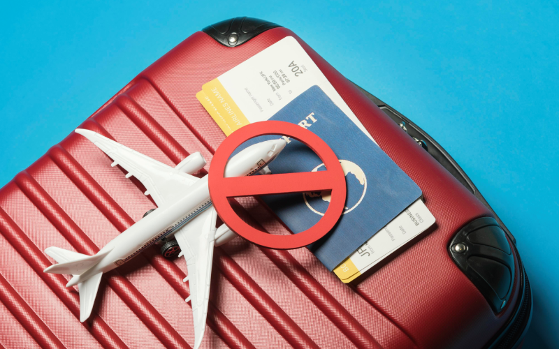 Top view of luggage, passport, ticket & airplane model with blue background
