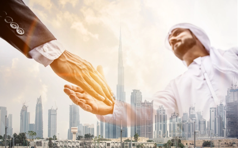 Double exposure of two business men over Dubai skyline building background. Arabian and western man handshaking concept