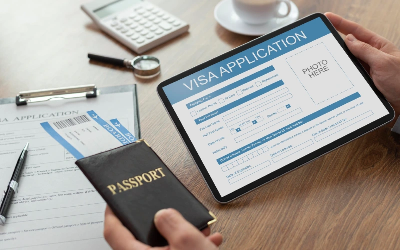 Hands holding tablet with online visa application and passport